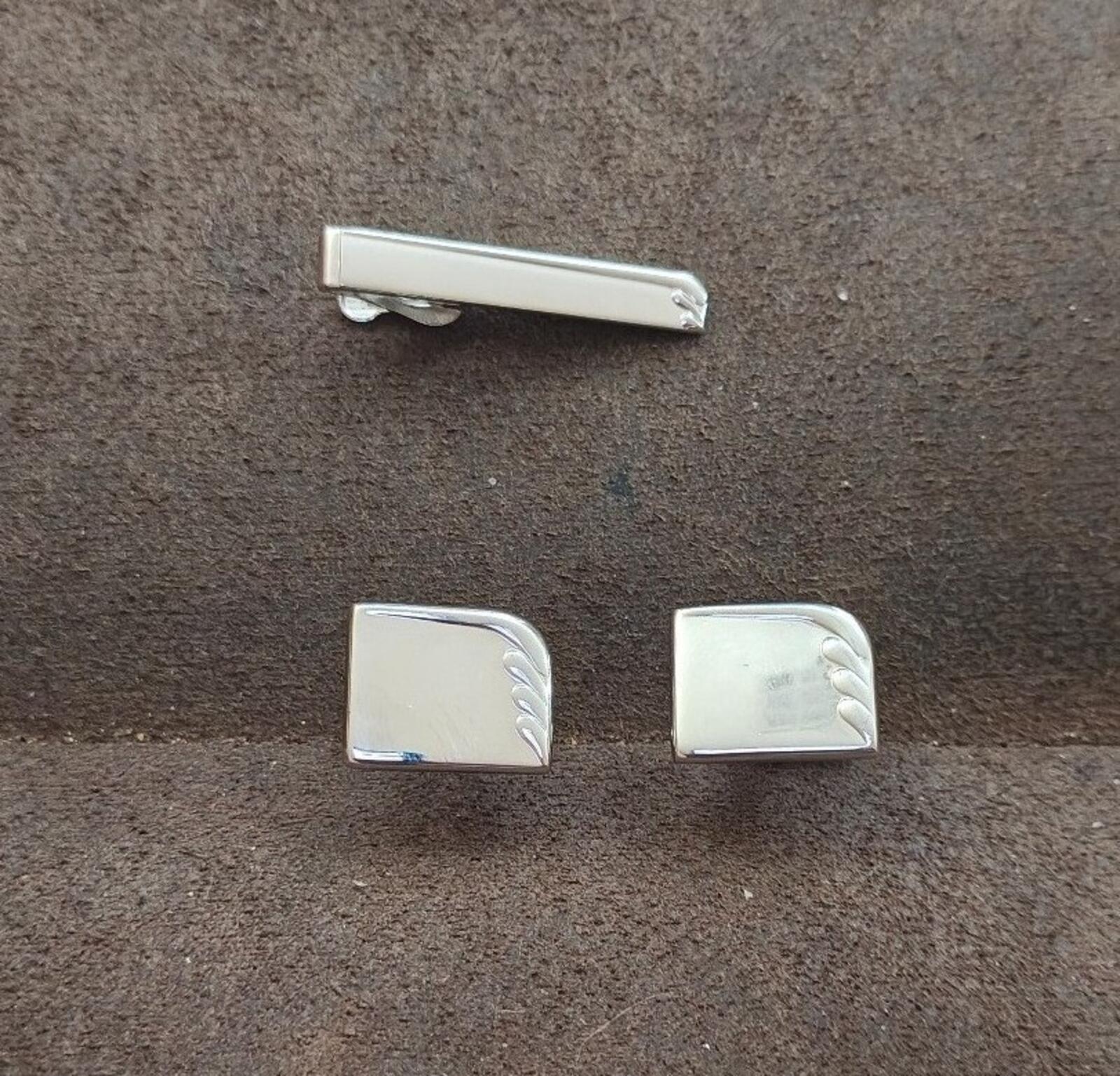 Silver tie bar with rounded ends and two rectangular cufflinks with decorative edge