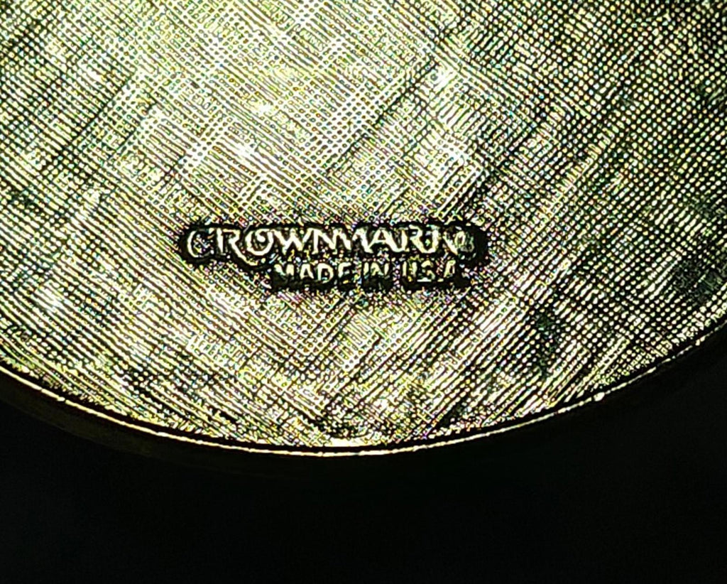 Close view of engraved maker text on round keychain back, gold-toned finish