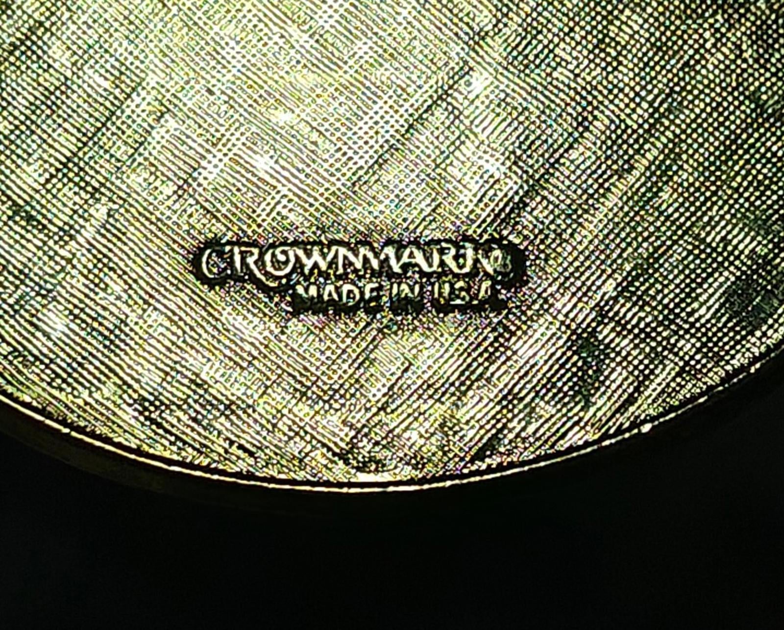 Close view of engraved maker text on round keychain back, gold-toned finish