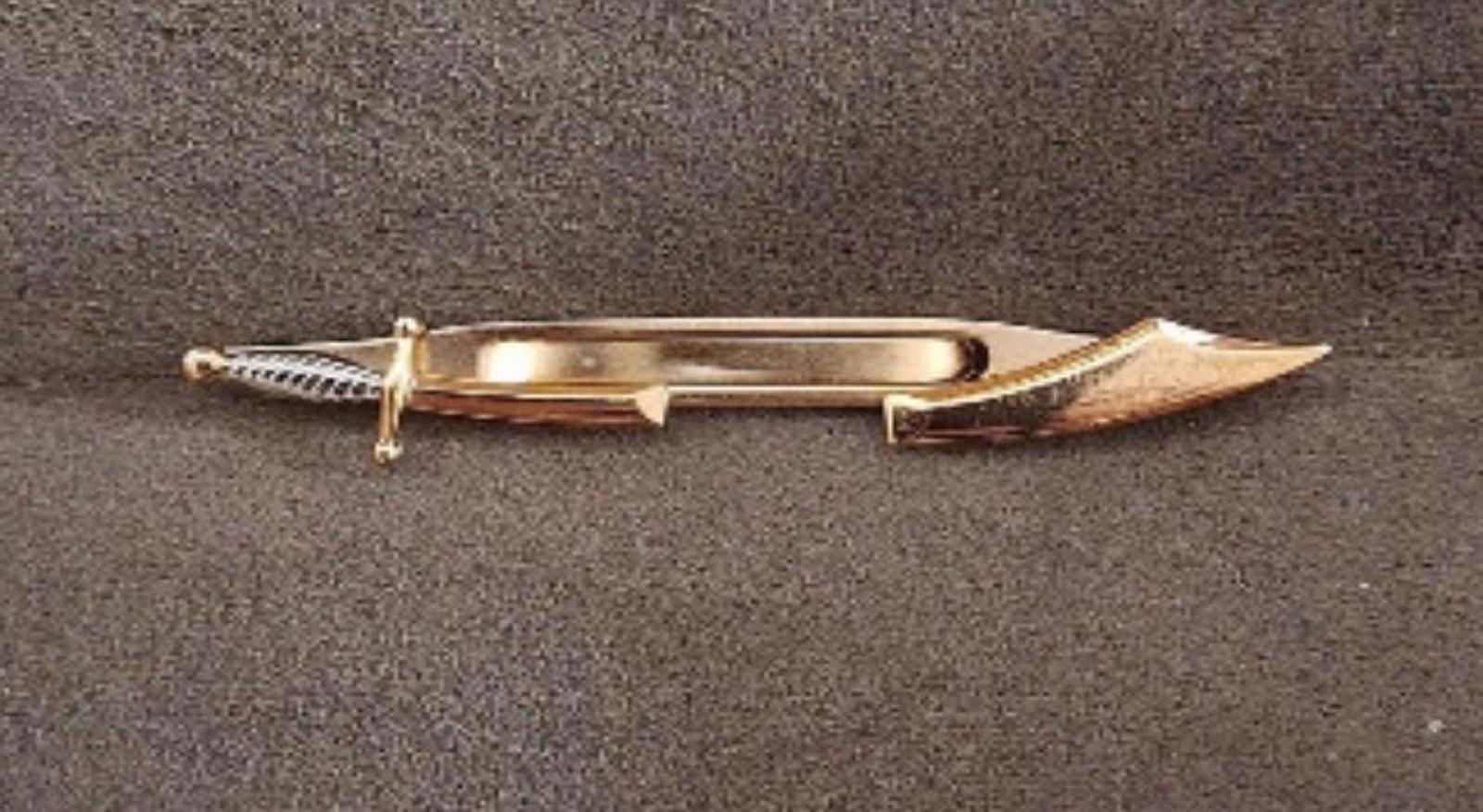 Gold pirate sword tie clip bar laid flat, showing ribbed handle and guard
