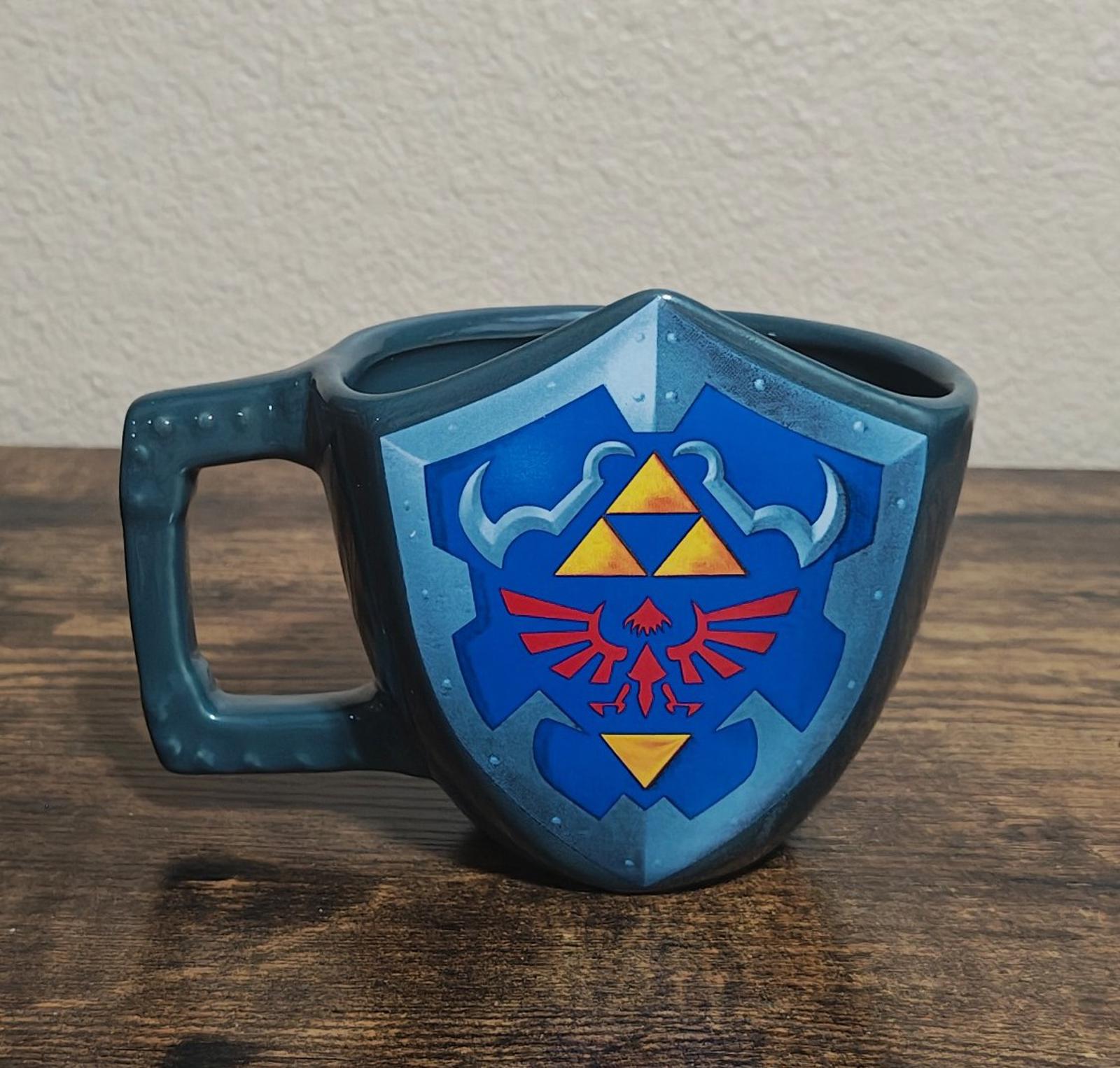 Blue mug with full Hylian shield graphic and handle, front view.