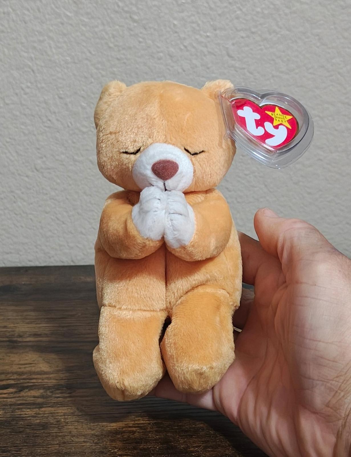 Brown plush bear holding white praying hands, with clear heart Ty tag on side