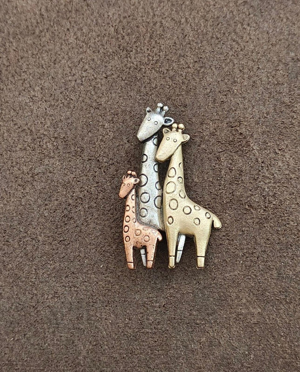 Tricolor giraffe family brooch with three giraffes stacked together in silver, gold, and brown