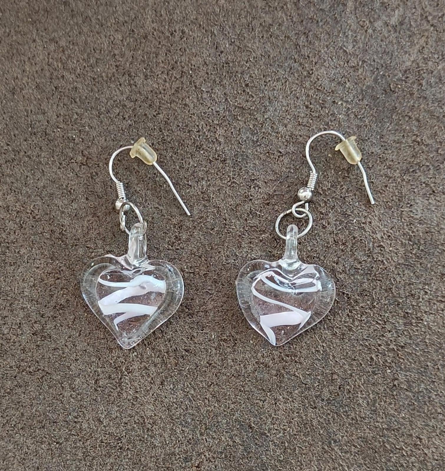 Pair of heart-shaped clear glass earrings with swirl detail and silver-tone hooks.