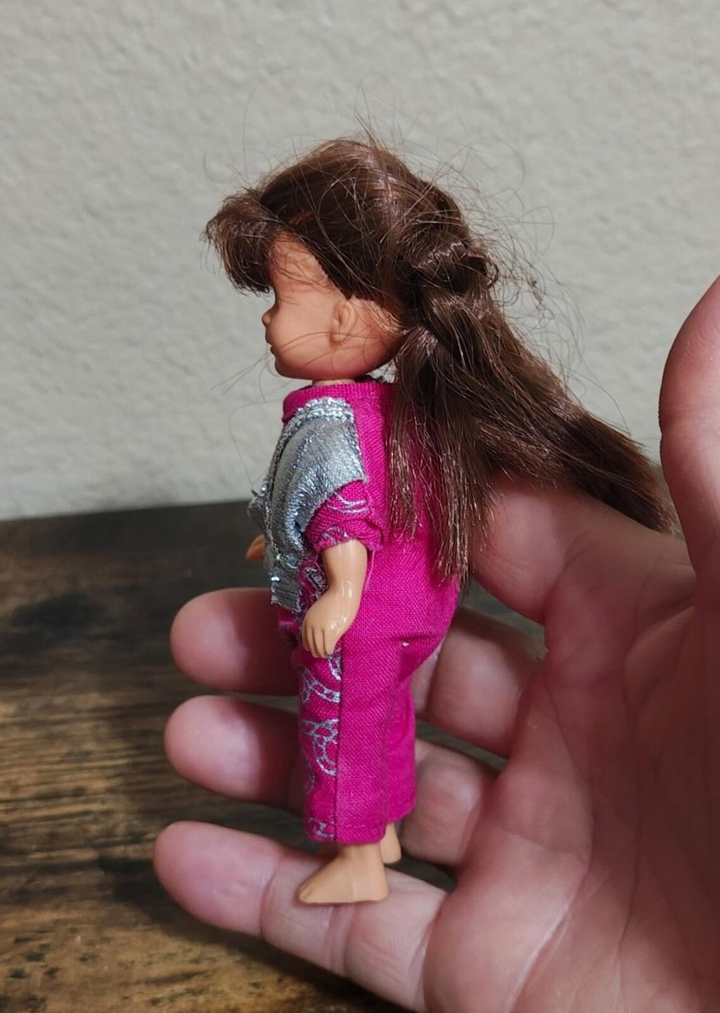 5-inch girl doll side view, long brown hair, blue eyes, pink romper with silver vest