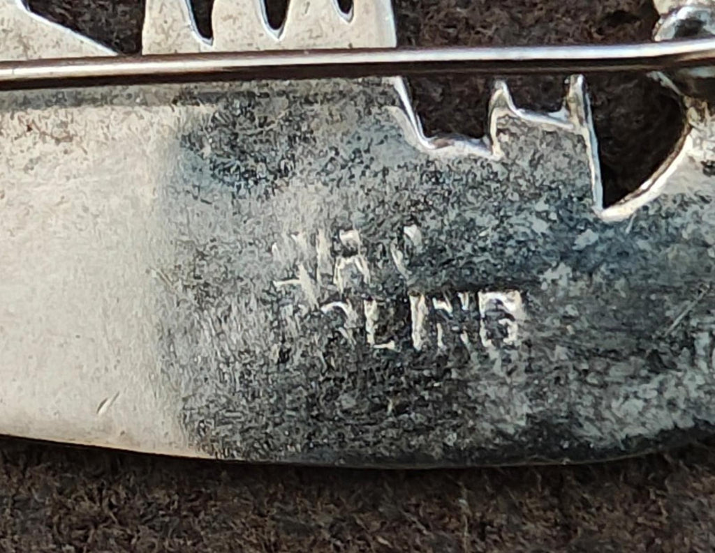 Sterling silver brooch close-up showing maker stamp and textured metal surface