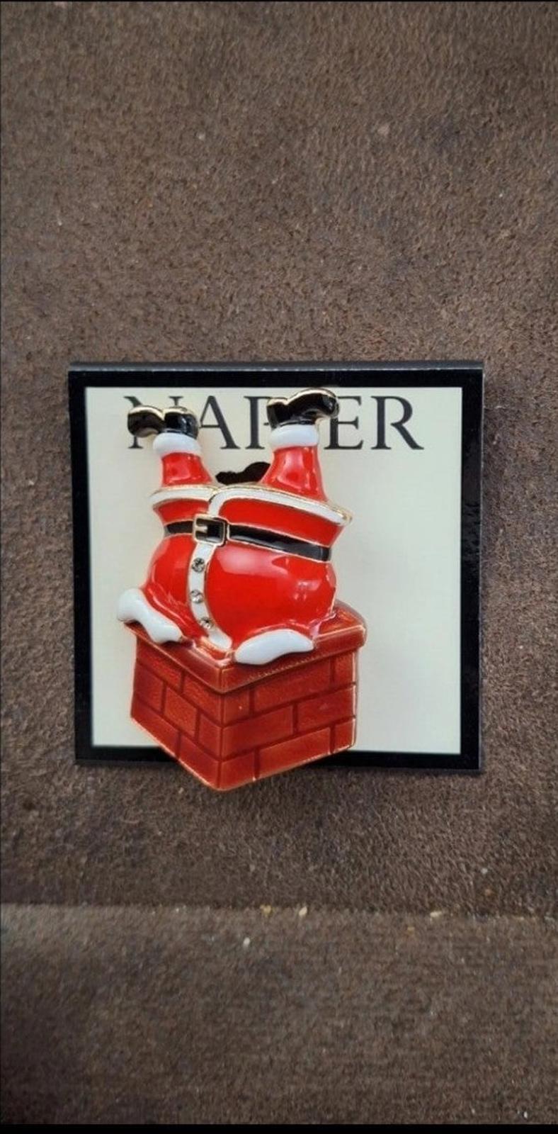 Red Santa climbing down chimney enamel pin on card, outdoor-style flat lay