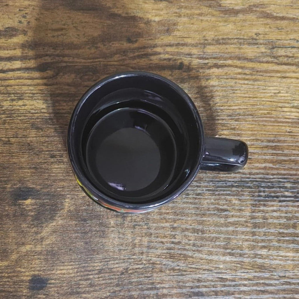 Black ceramic mug bottom with unglazed center and small decorative skyline color details