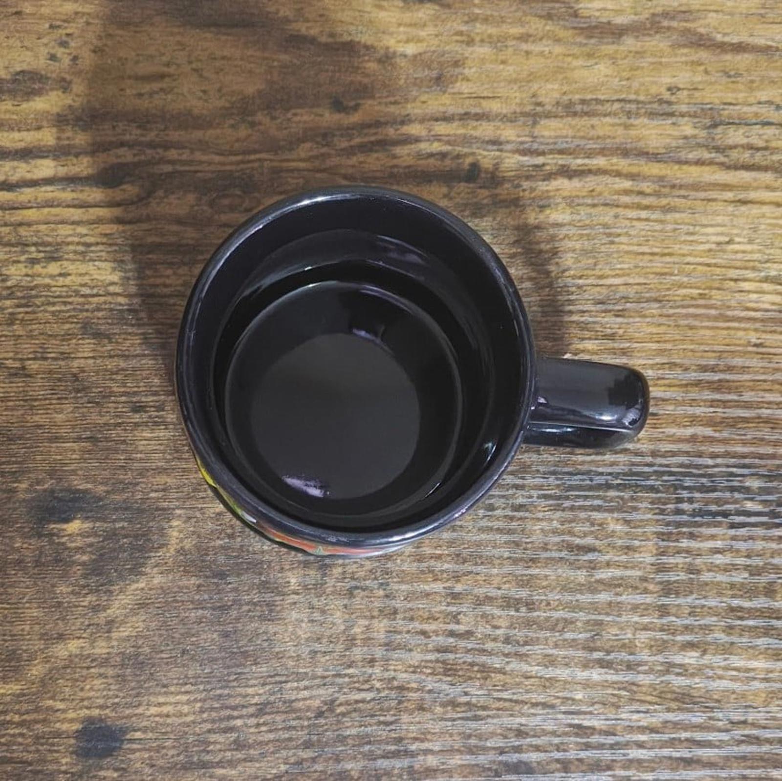 Black ceramic mug bottom with unglazed center and small decorative skyline color details