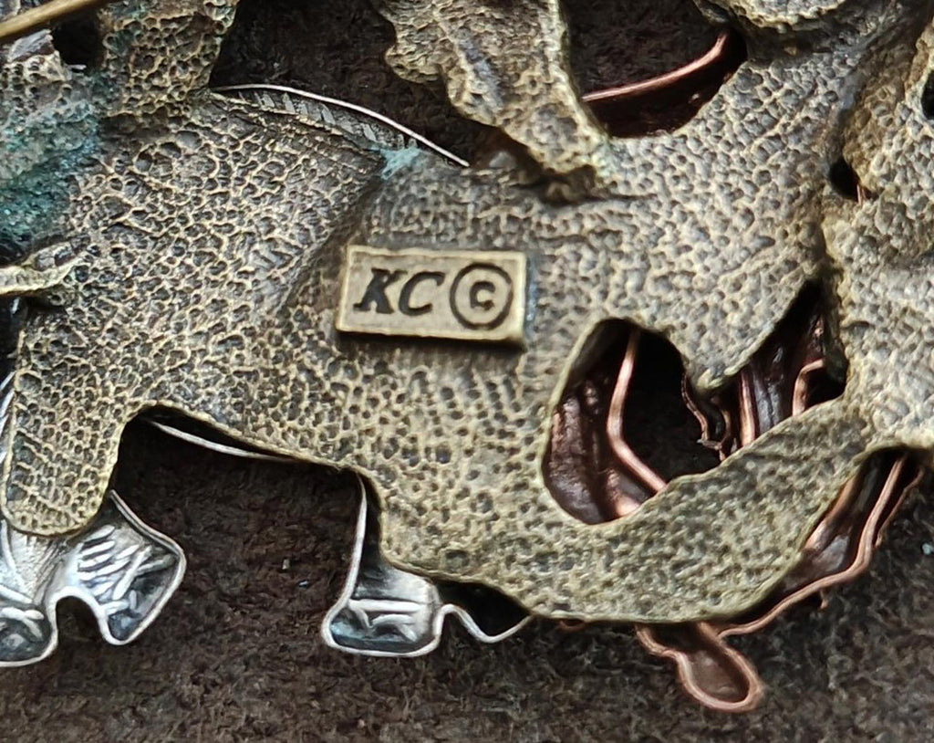 Close-up of safari brooch back with "XC" stamp and textured metal finish