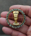 Gold-tone round brooch with Nefertiti profile medallion and blue rhinestone bezel