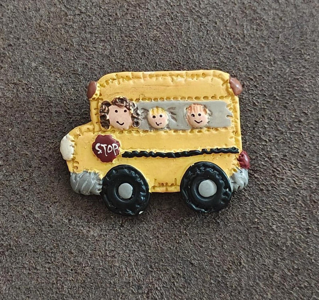 Yellow school bus resin pin with cartoon kids, red STOP sign, and black wheels
