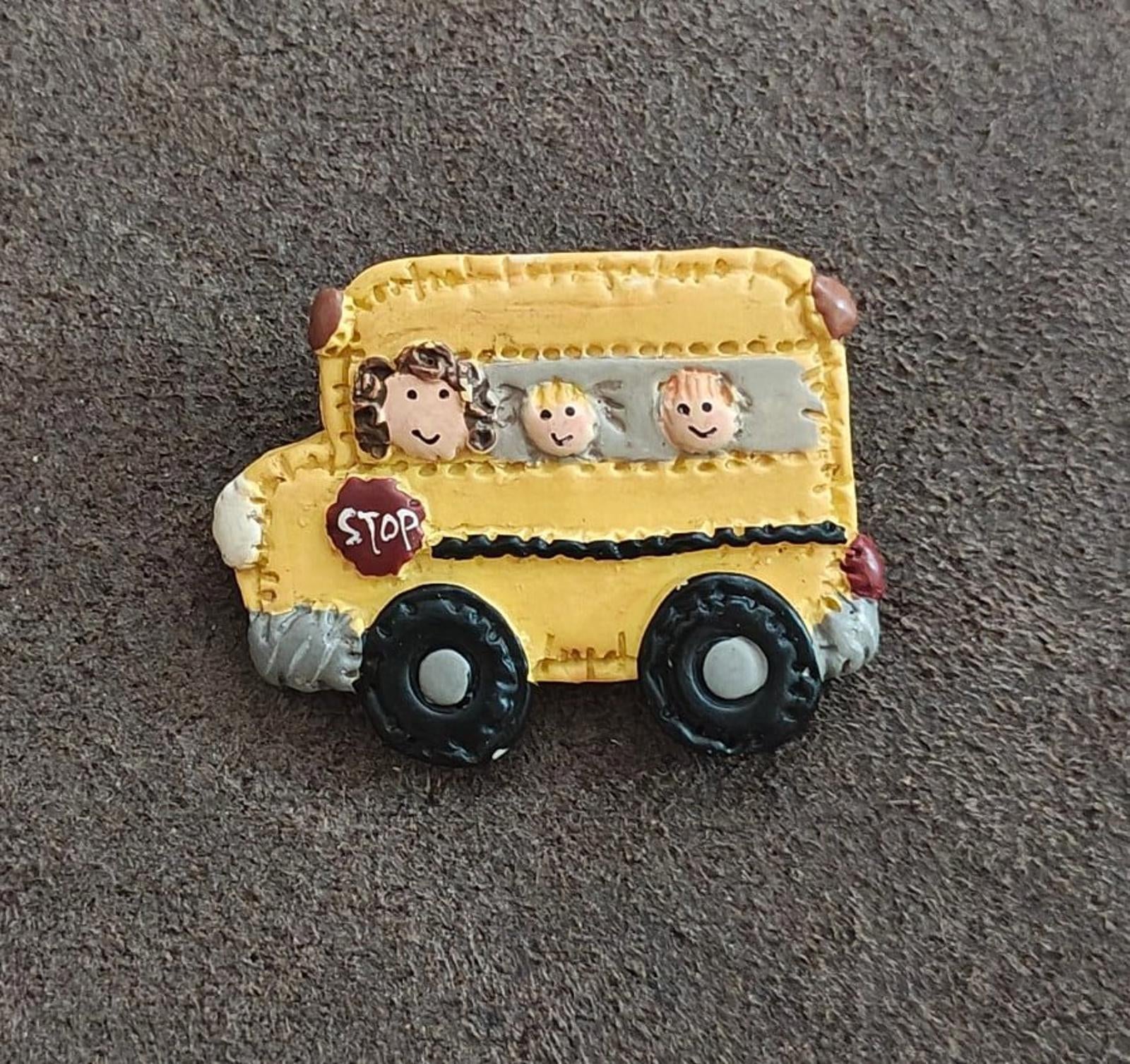 Yellow school bus resin pin with cartoon kids, red STOP sign, and black wheels