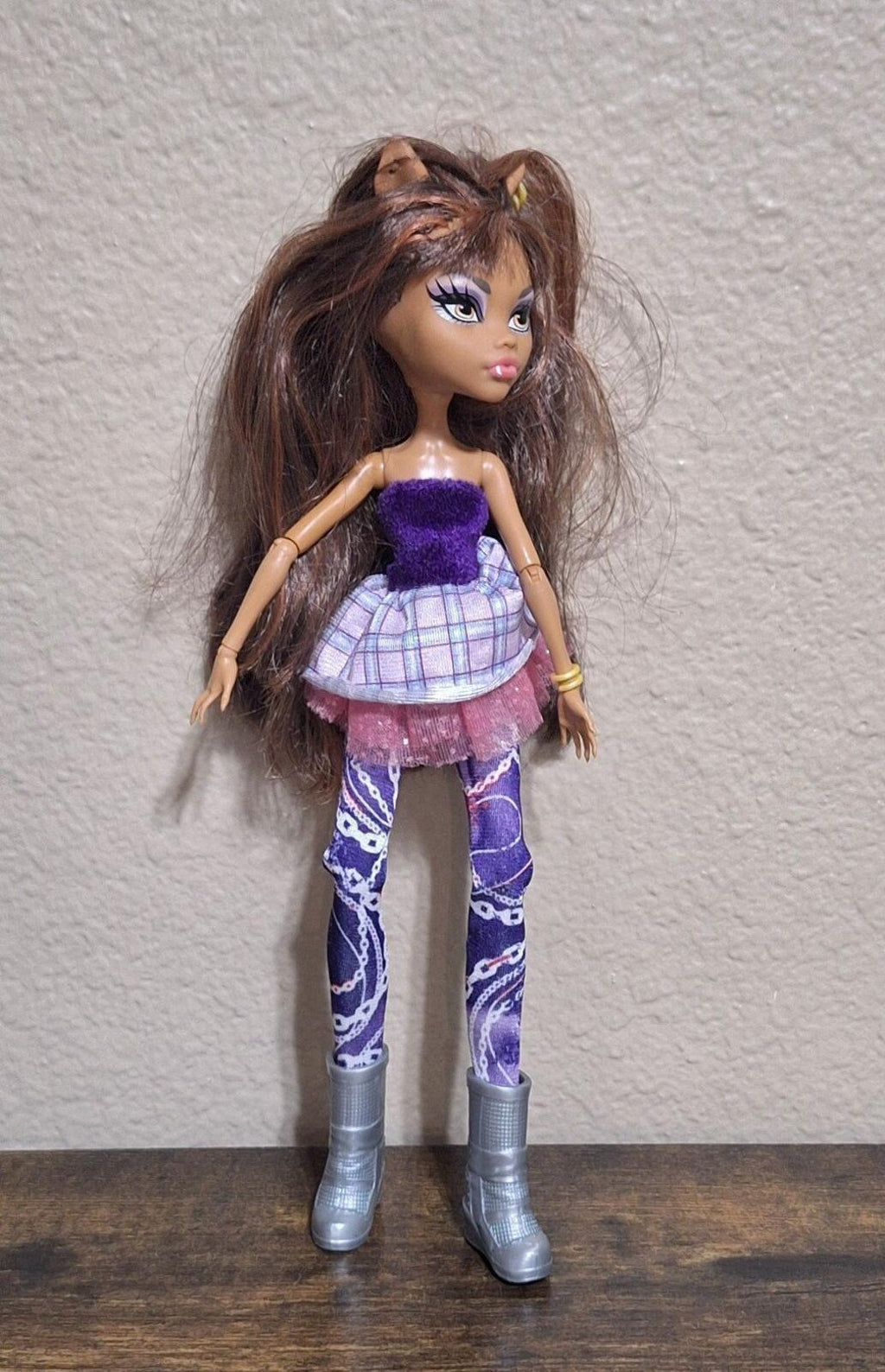 Fashion doll full view with purple glitter top, plaid ruffled skirt, and purple leggings