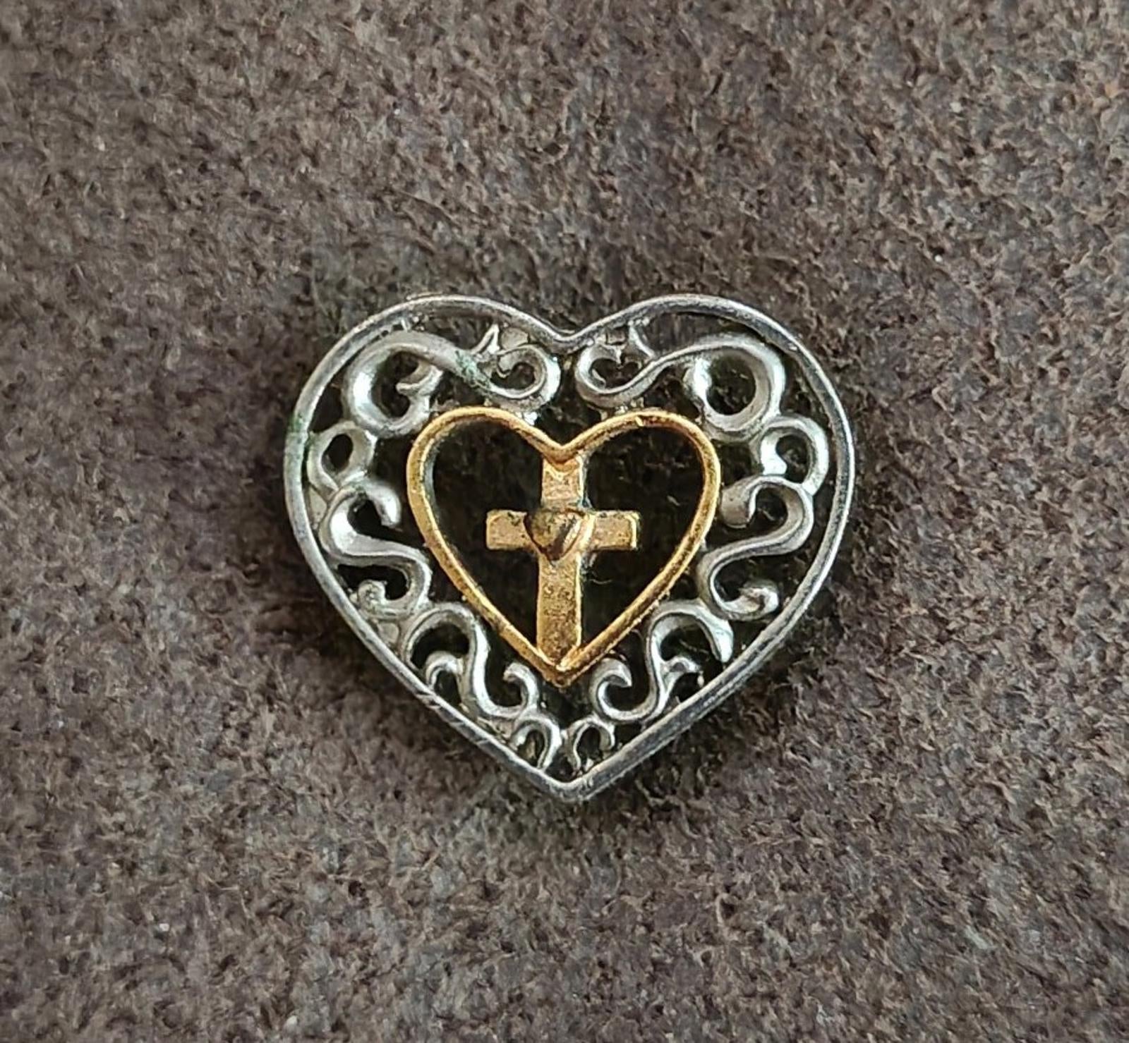 Heart cross pin on textured surface, gold-toned heart outline and cross in center