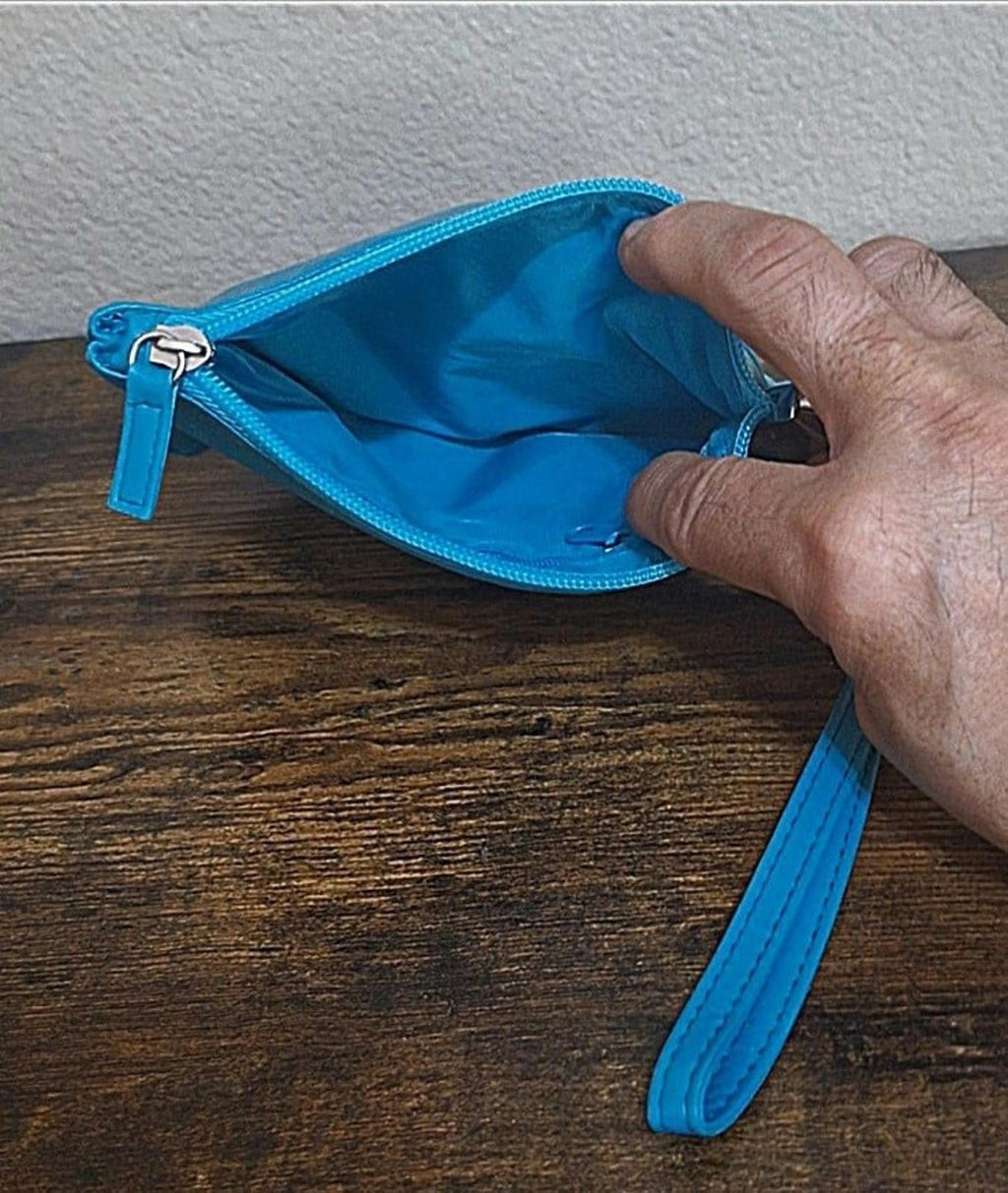 Teal clutch purse with zipper and wrist strap, open interior shown by hand