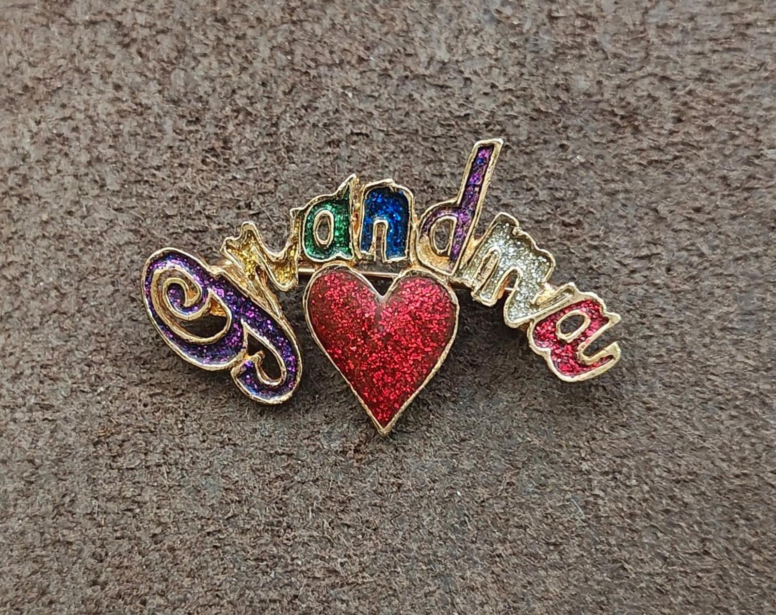 Gold tone grandma brooch with centered red glitter heart and rainbow enamel details