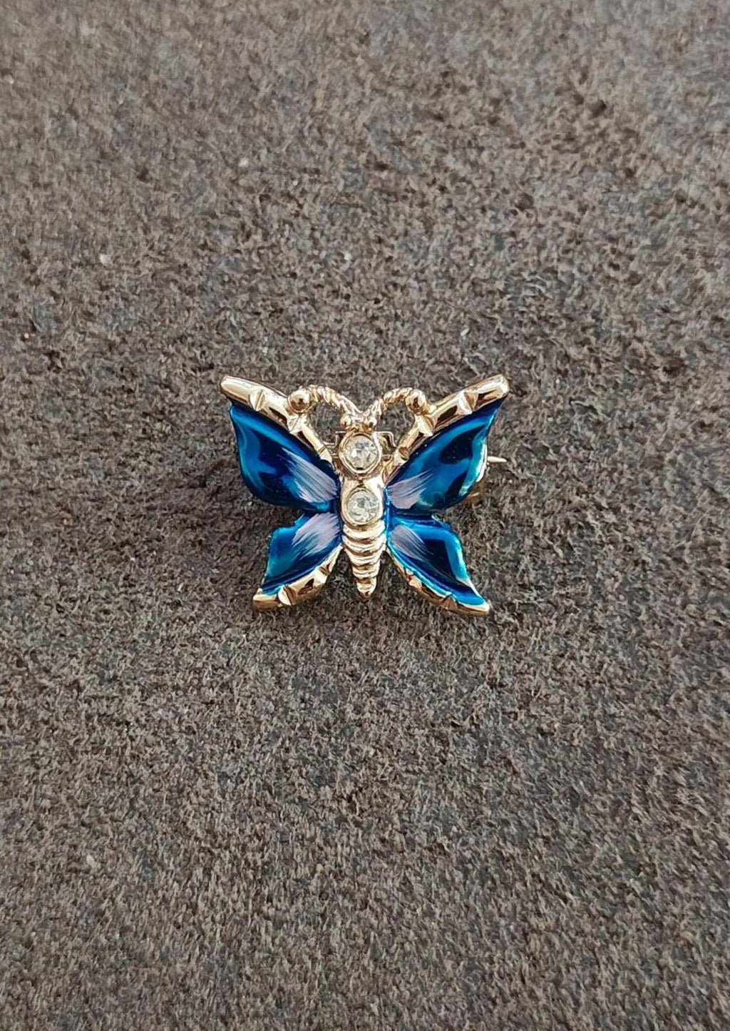Gold tone butterfly brooch with blue enamel wings and clear rhinestone centers