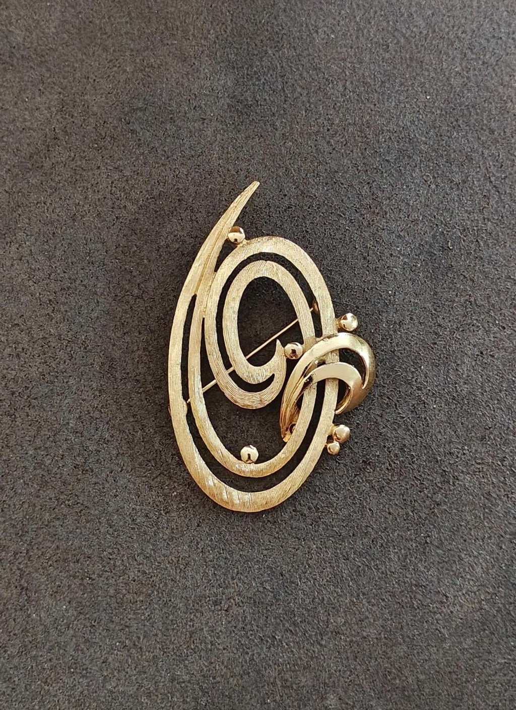 Gold tone oval brooch pin with double swirl pattern and ball-like accent details