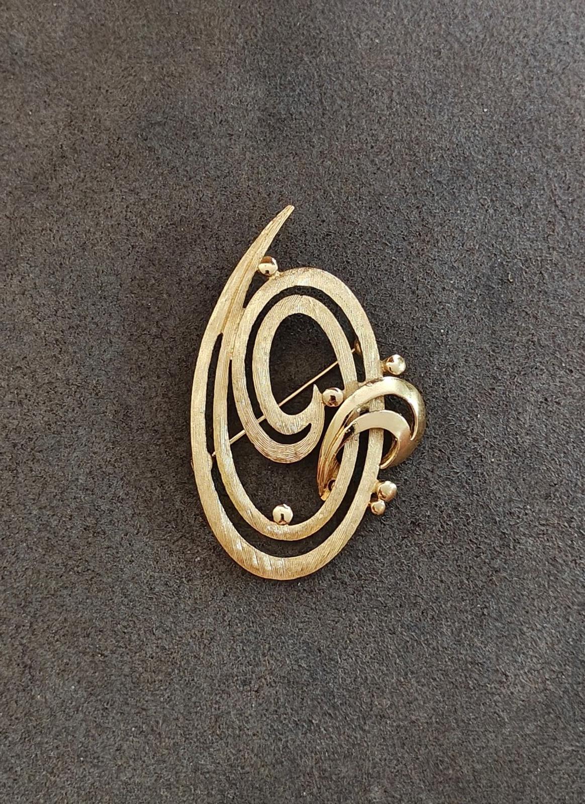 Gold tone oval brooch pin with double swirl pattern and ball-like accent details
