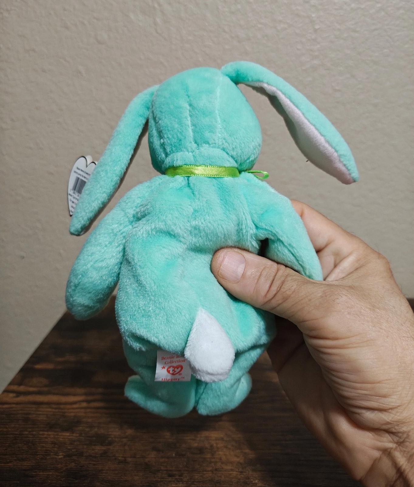 Teal plush bunny beanbag shown from behind with green ribbon belt and paw detail