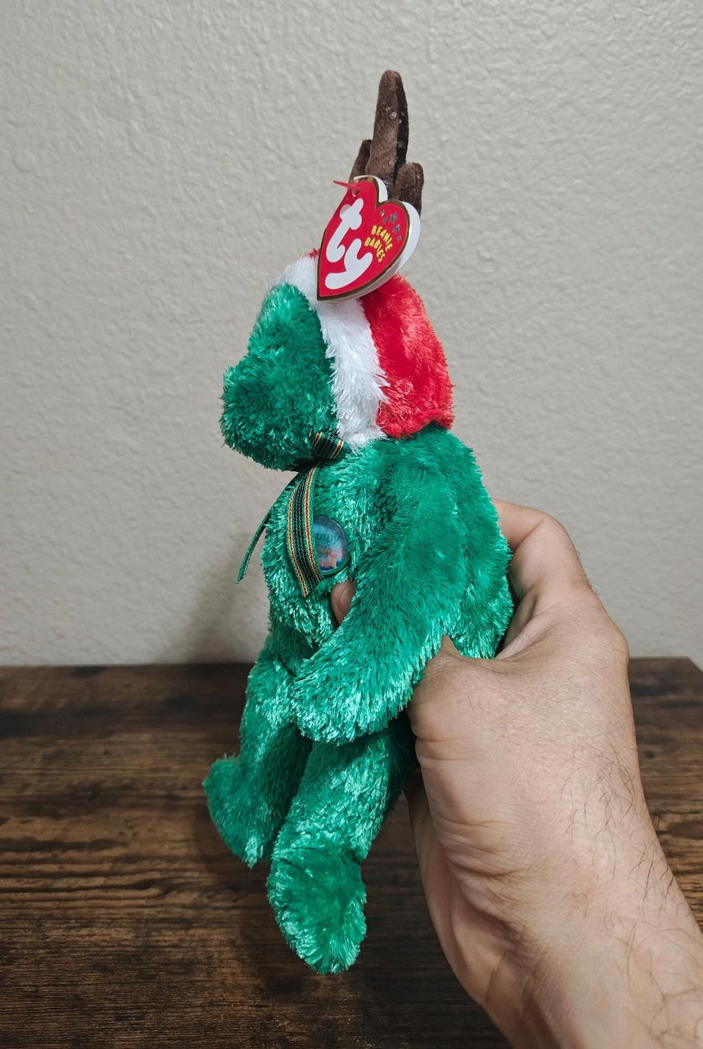 Green plush reindeer teddy bear sitting with antlers, red-and-white hat, TY tag