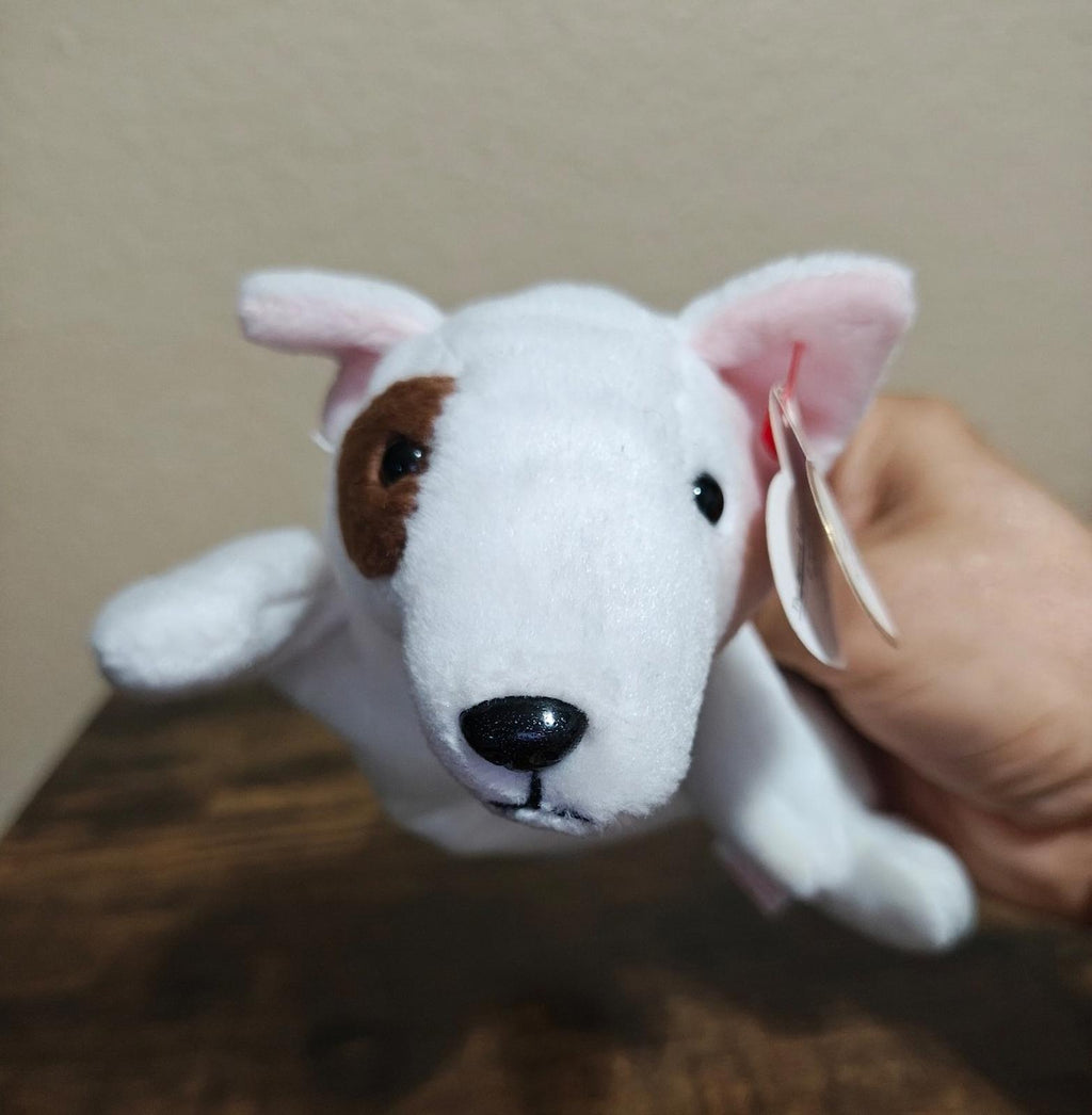 White plush dog face with brown ear patch and red Ty heart tag, close-up