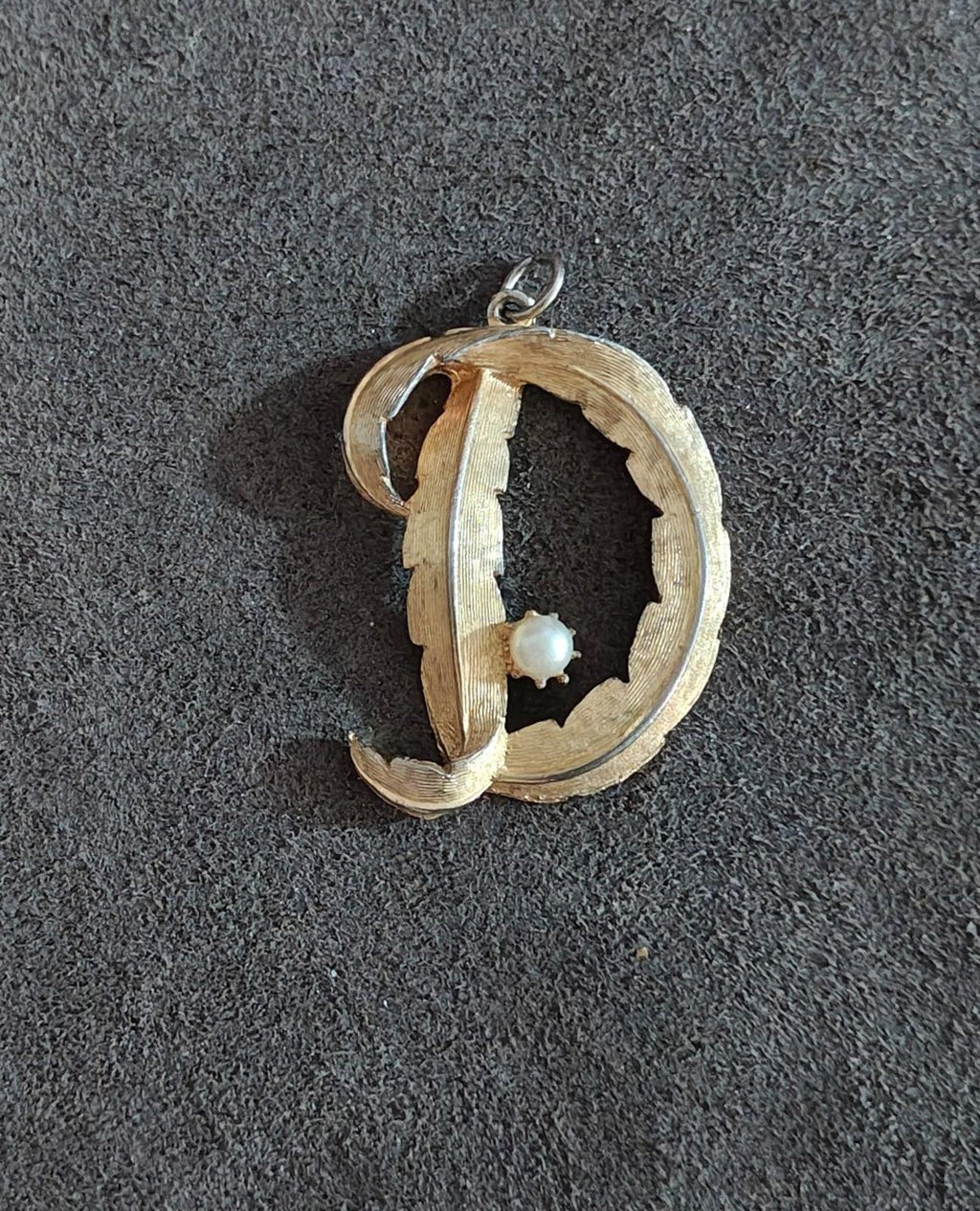 Gold-tone letter D monogram pendant with small white pearl center and hanging loop