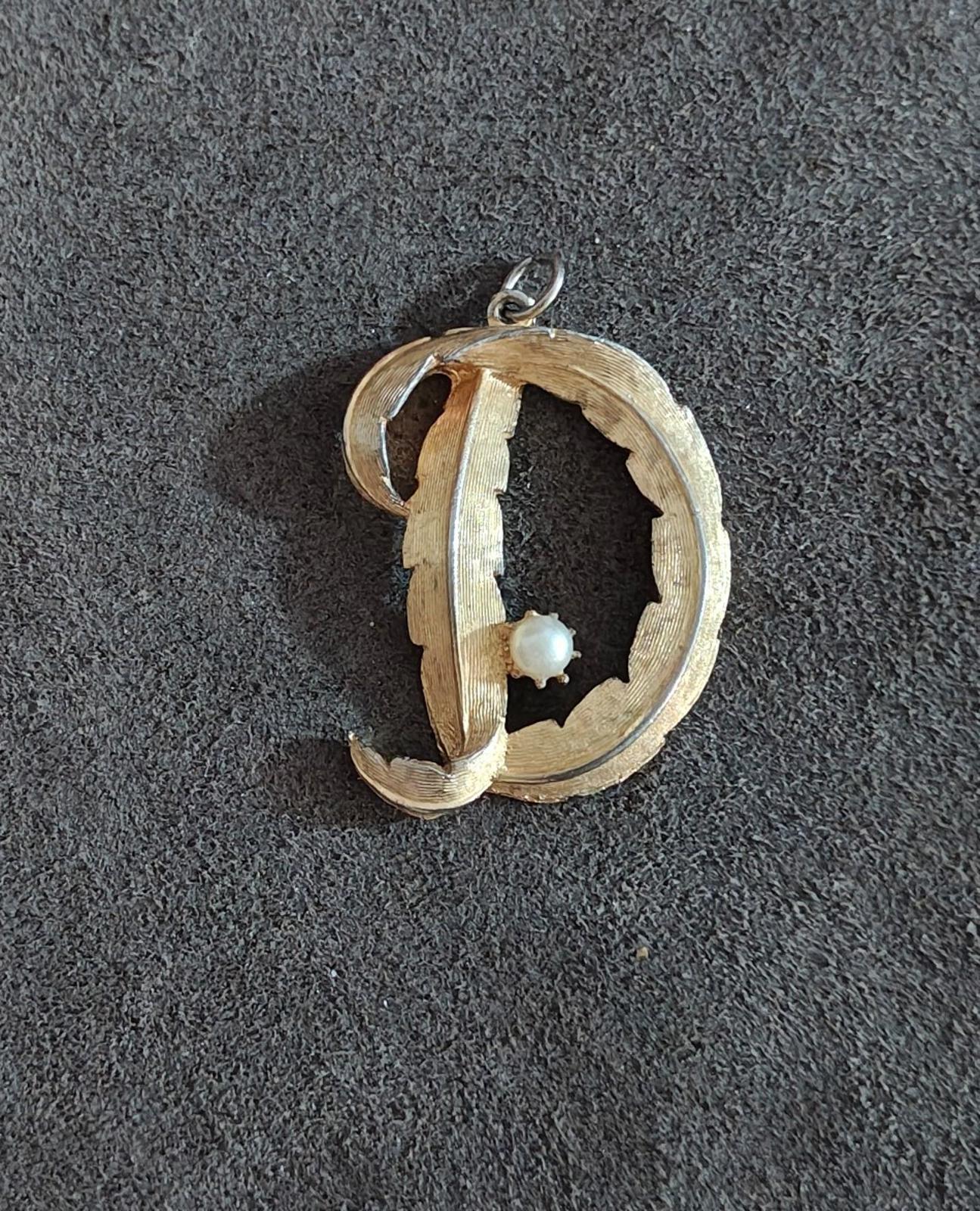 Gold-tone letter D monogram pendant with small white pearl center and hanging loop