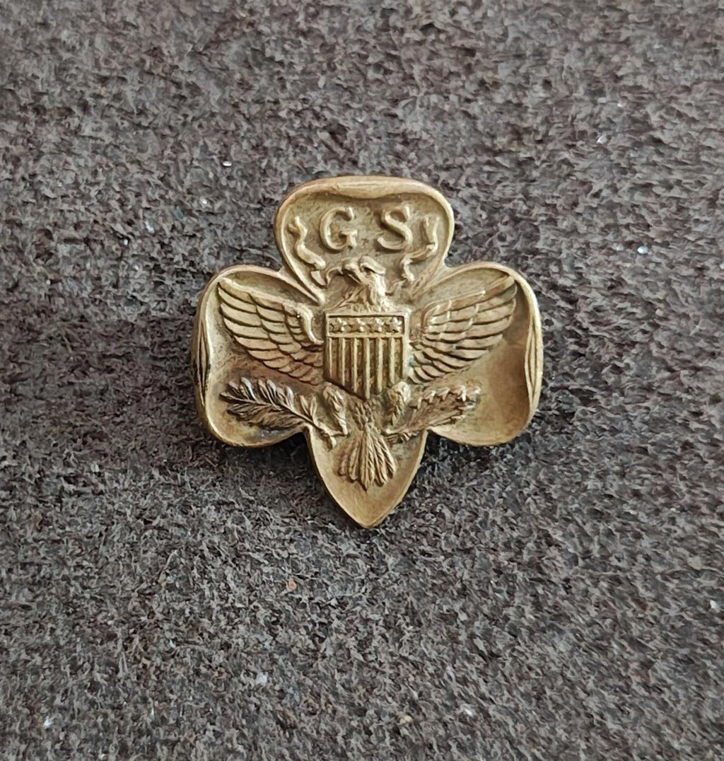 Gold-tone Girl Scout eagle brooch pin with GS crest and shield, centered on dark surface