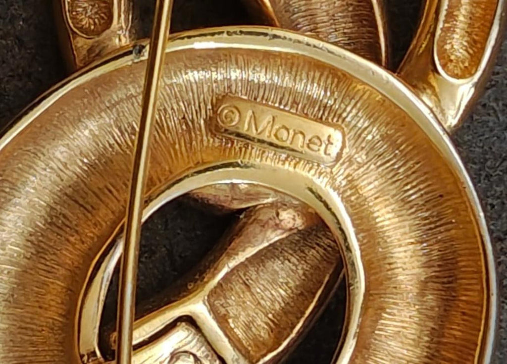 Monet gold-tone pin brooch close-up showing 'Monet' hallmark