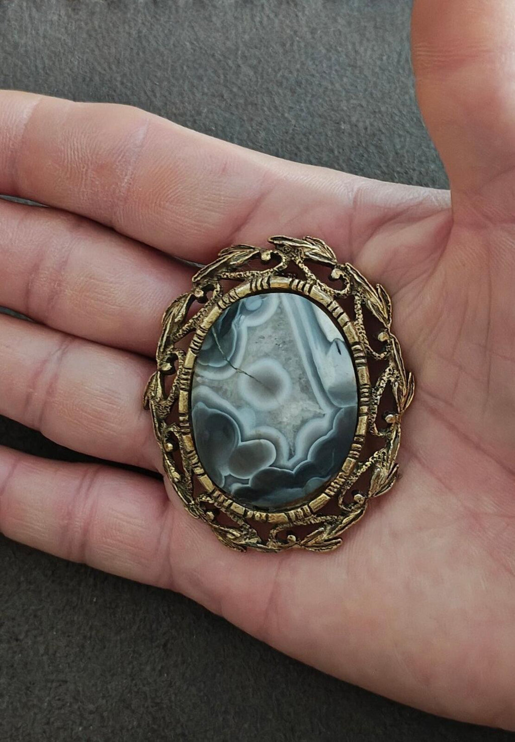 Vintage framed agate cabochon pendant on hand view, oval blue cabochon in goldtone setting