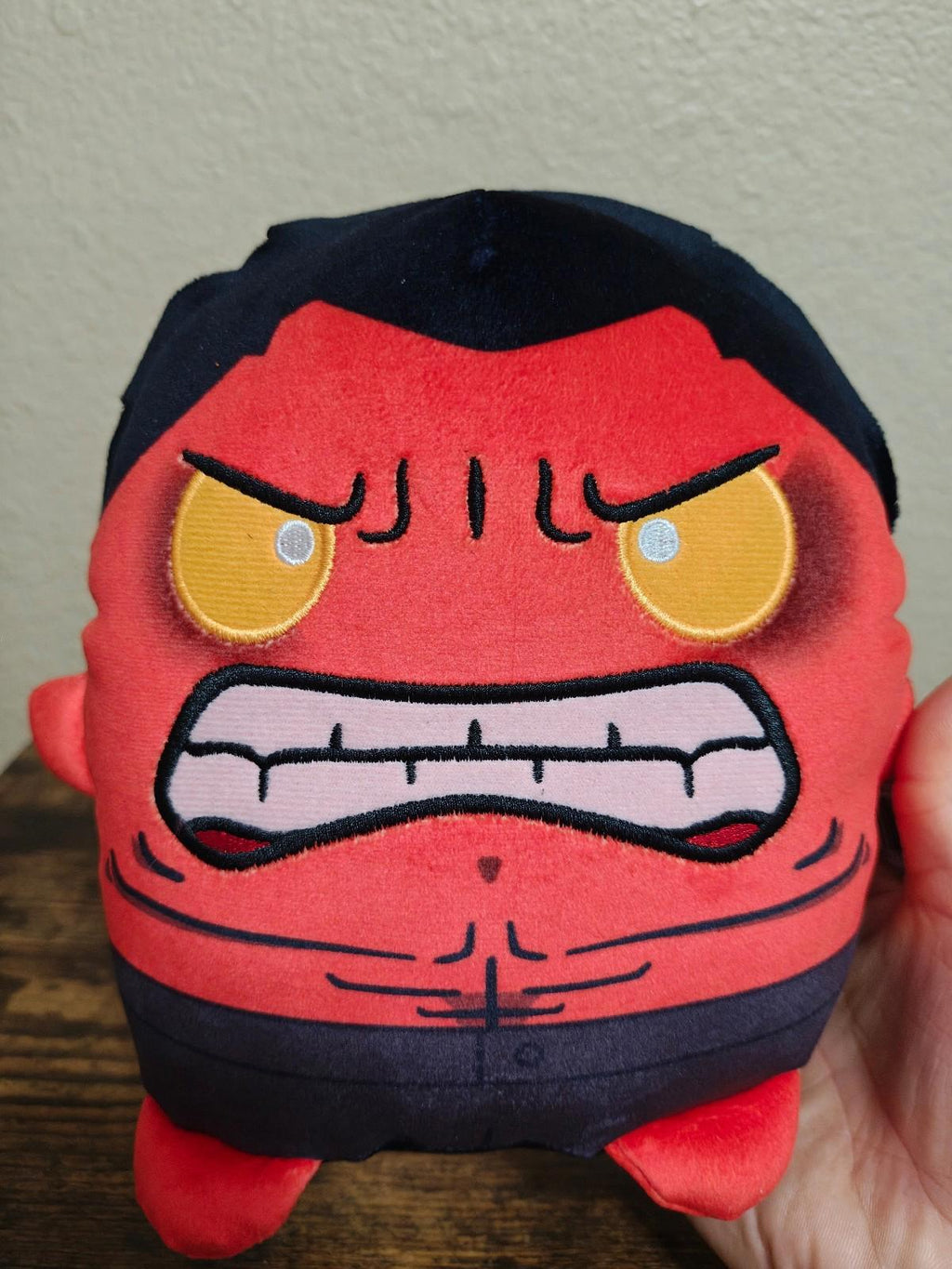 Front view of red and navy angry-faced soft plush toy with yellow eyes