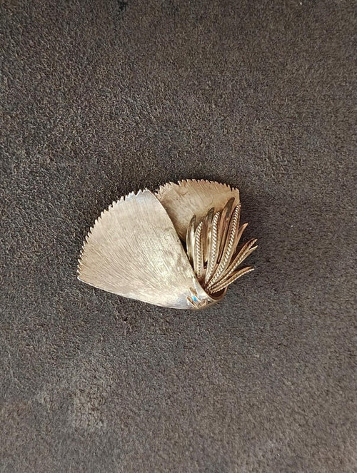 Leaf-shaped gold-tone brooch with layered gold fronds and tiny blue center stone