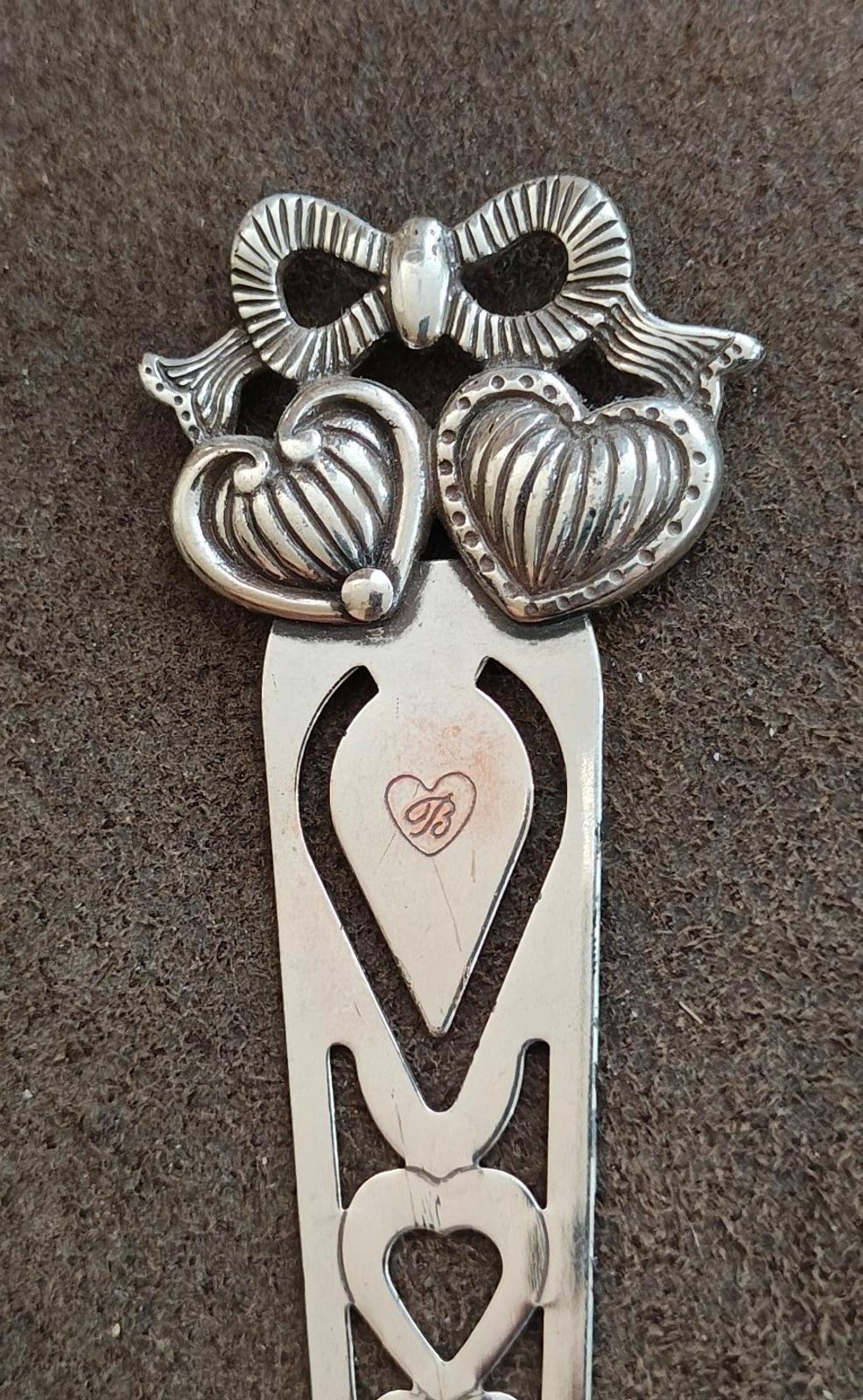 Silver plated letter opener bookmark close-up with heart designs and bow-shaped top