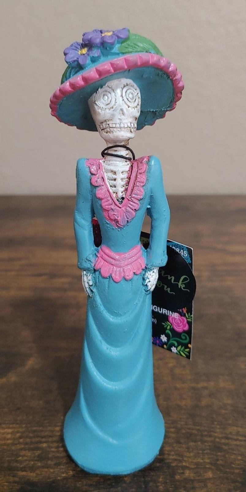 Day of the Dead lady figurine with sugar skull face, blue dress and decorated sombrero