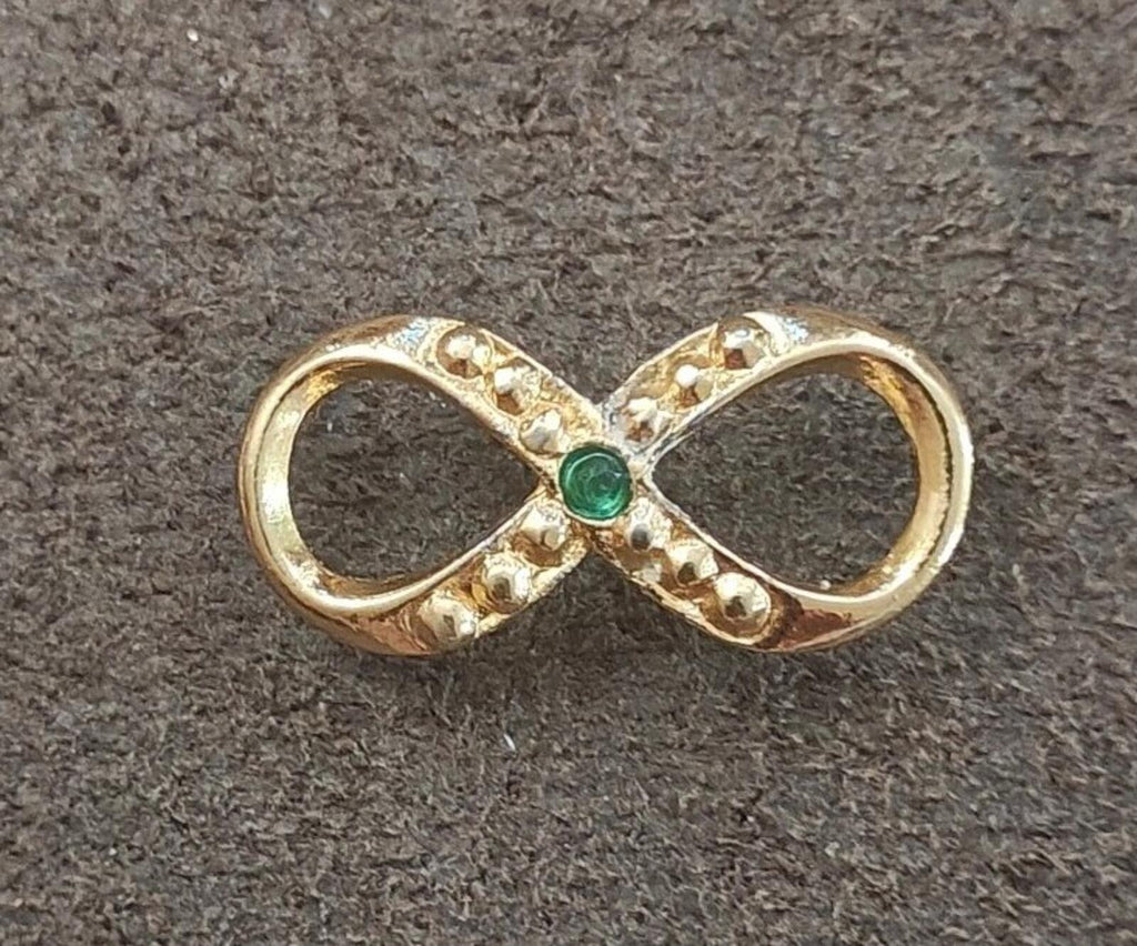 Gold infinity brooch with green emerald center and glittering clear stones