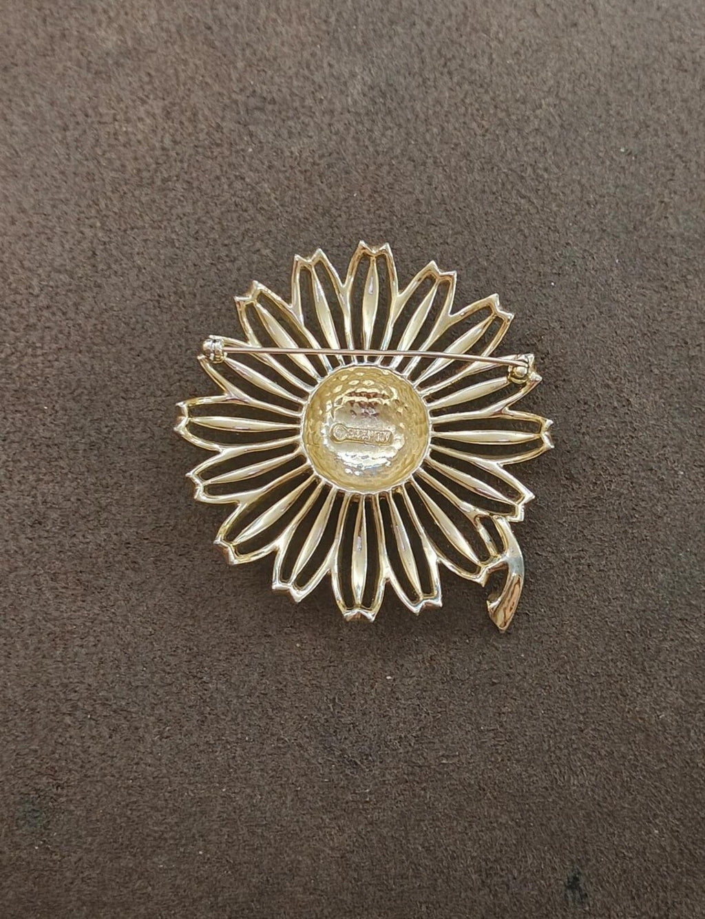 Gold tone sunflower brooch from back view, ridged petal rays around central stamp