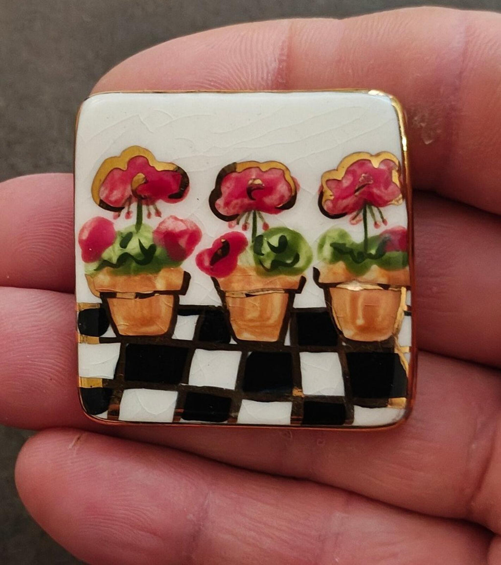 Square glazed ceramic flower brooch with pink blossoms, potted plants, and black checker design
