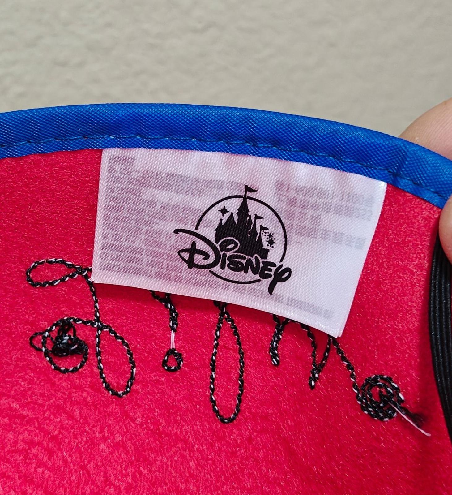 Red felt hat with fabric label showing Disney logo and black hanging string ties