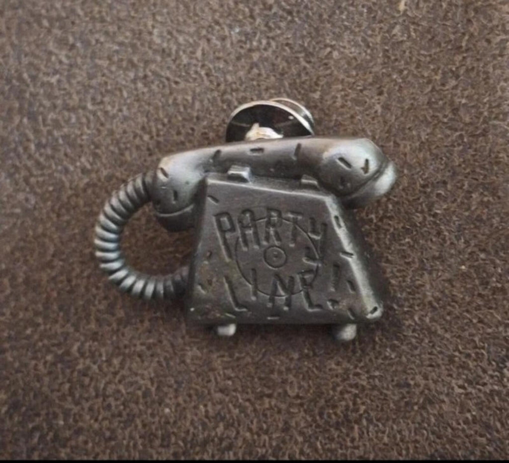Silver telephone novelty pin, angled front view with 'PARTY LINE' engraving and cord detail