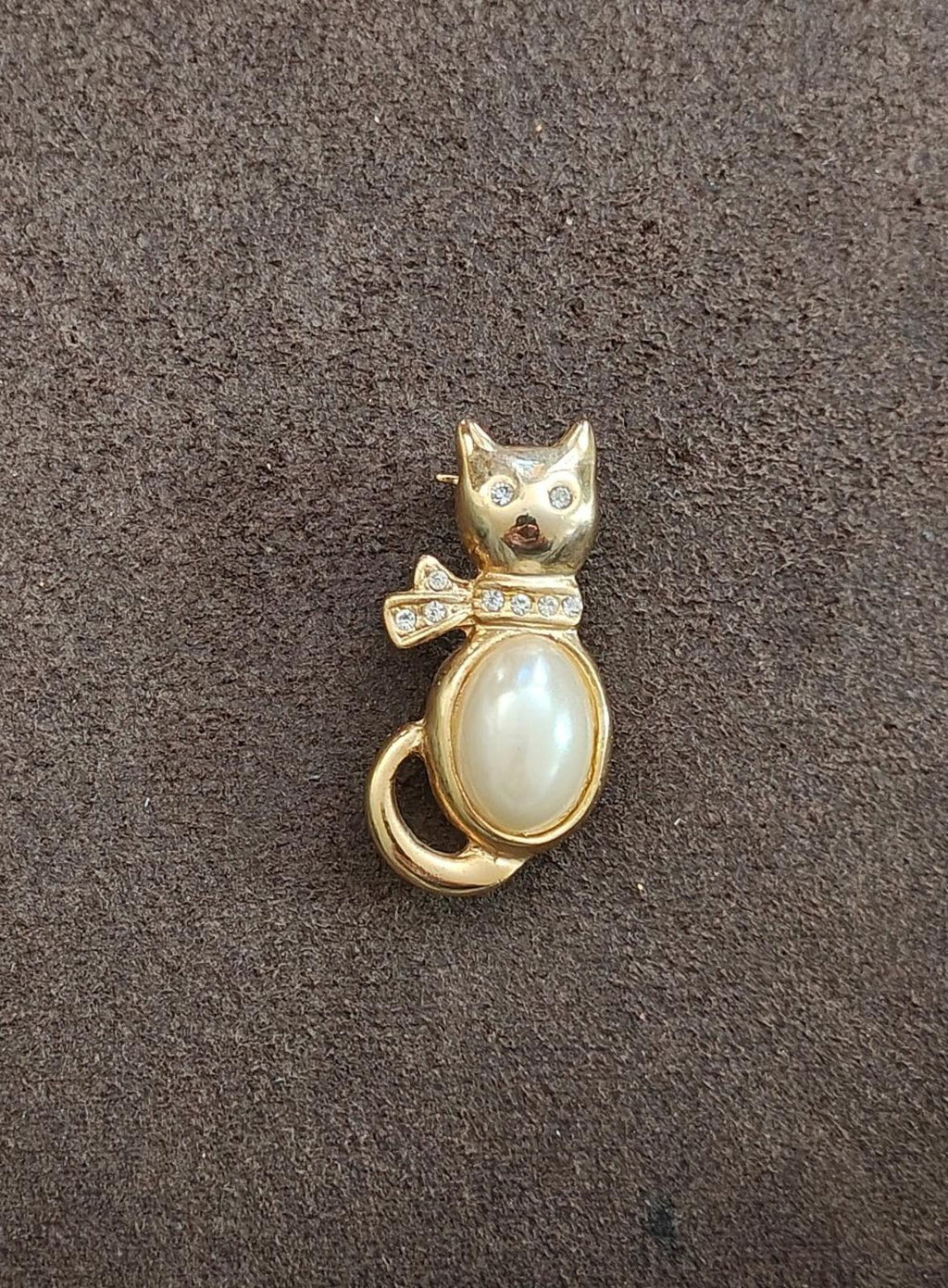 Gold-tone cat brooch with oval faux pearl, rhinestone bow, and small face gems