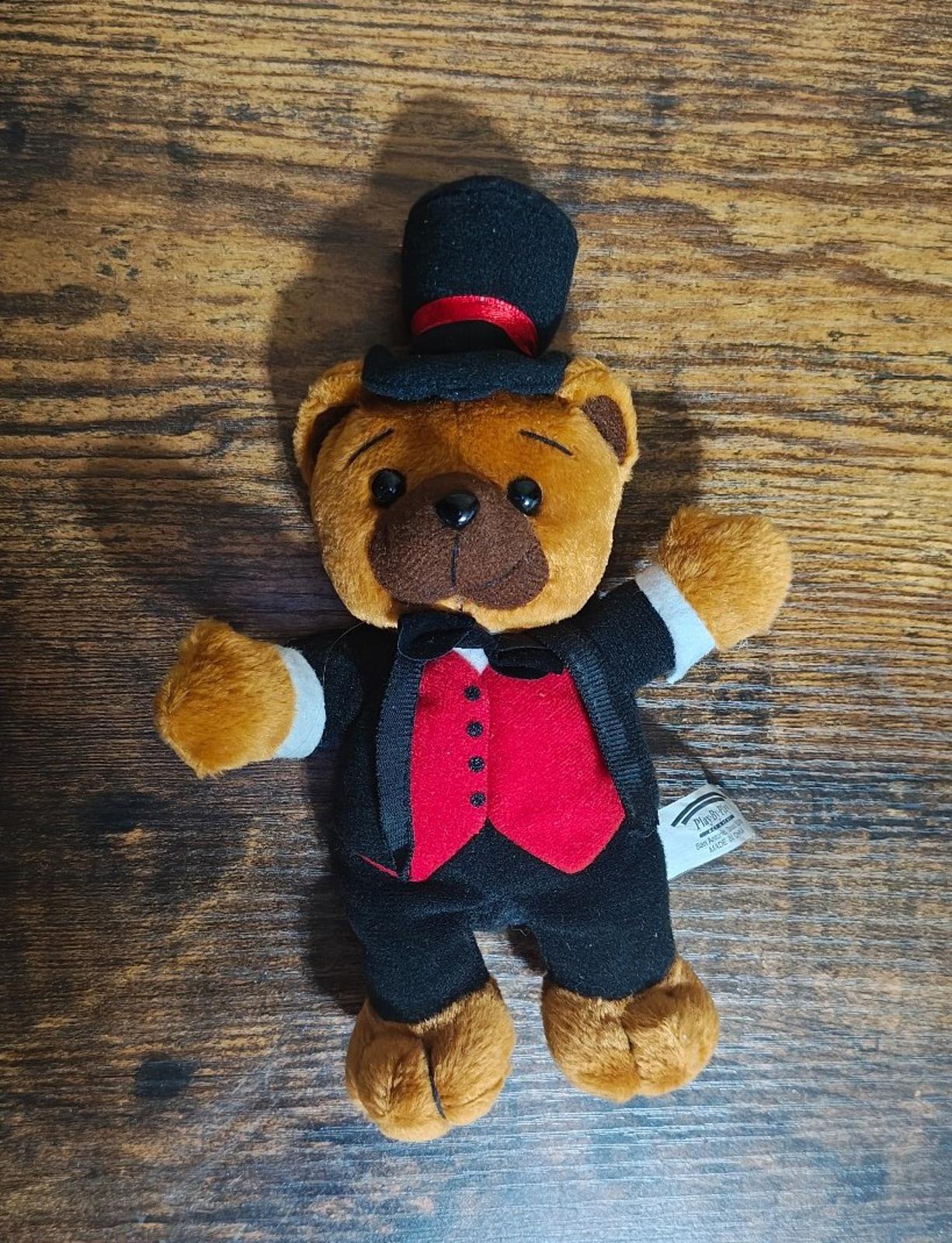 Standing plush bear facing up with black top hat, red vest, and white shirt cuffs.