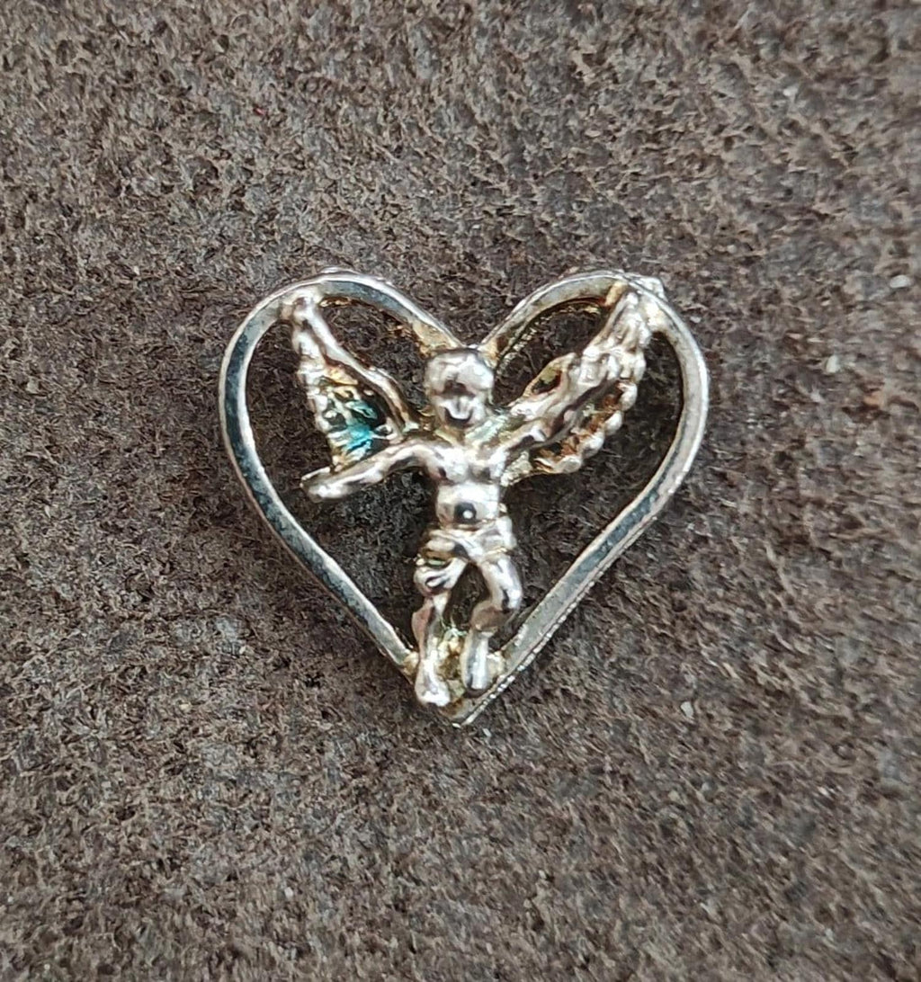 Silver-tone winged angel heart pin on dark textured background, full front view