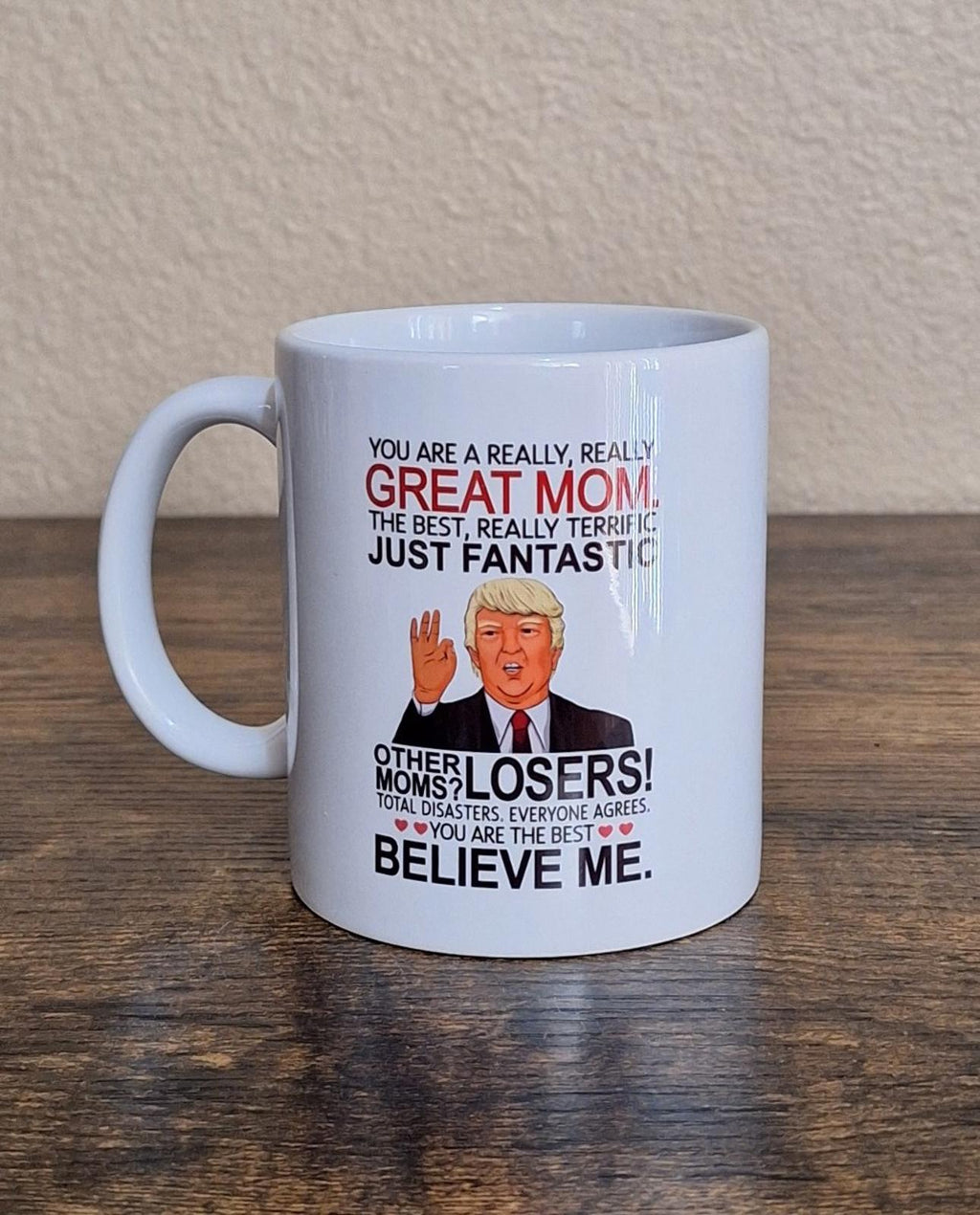 White ceramic 11 oz mug on wooden surface with “Great Mom” text and portrait graphic