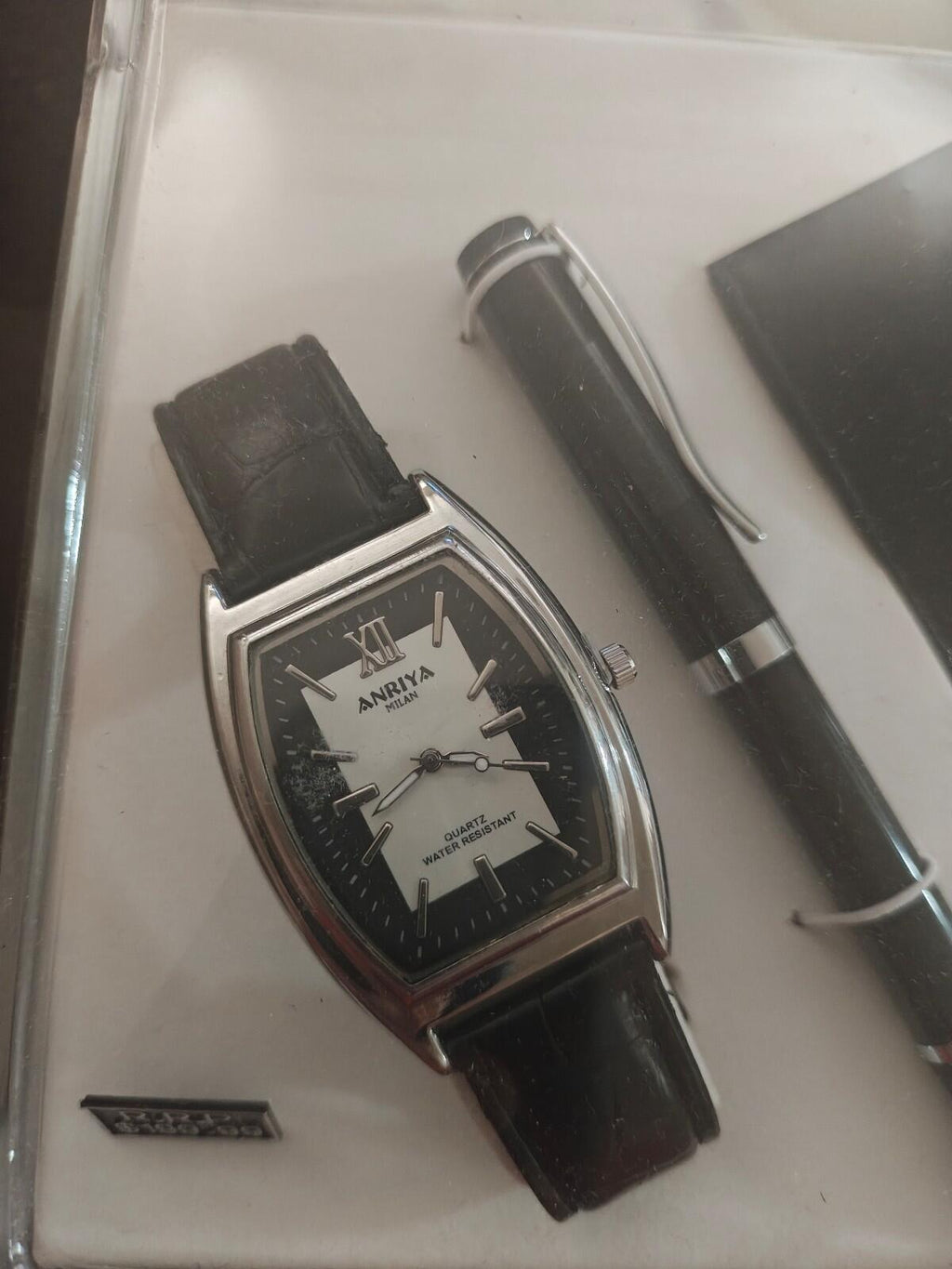 Close view of black wristwatch with matching pen and cardholder in set tray.
