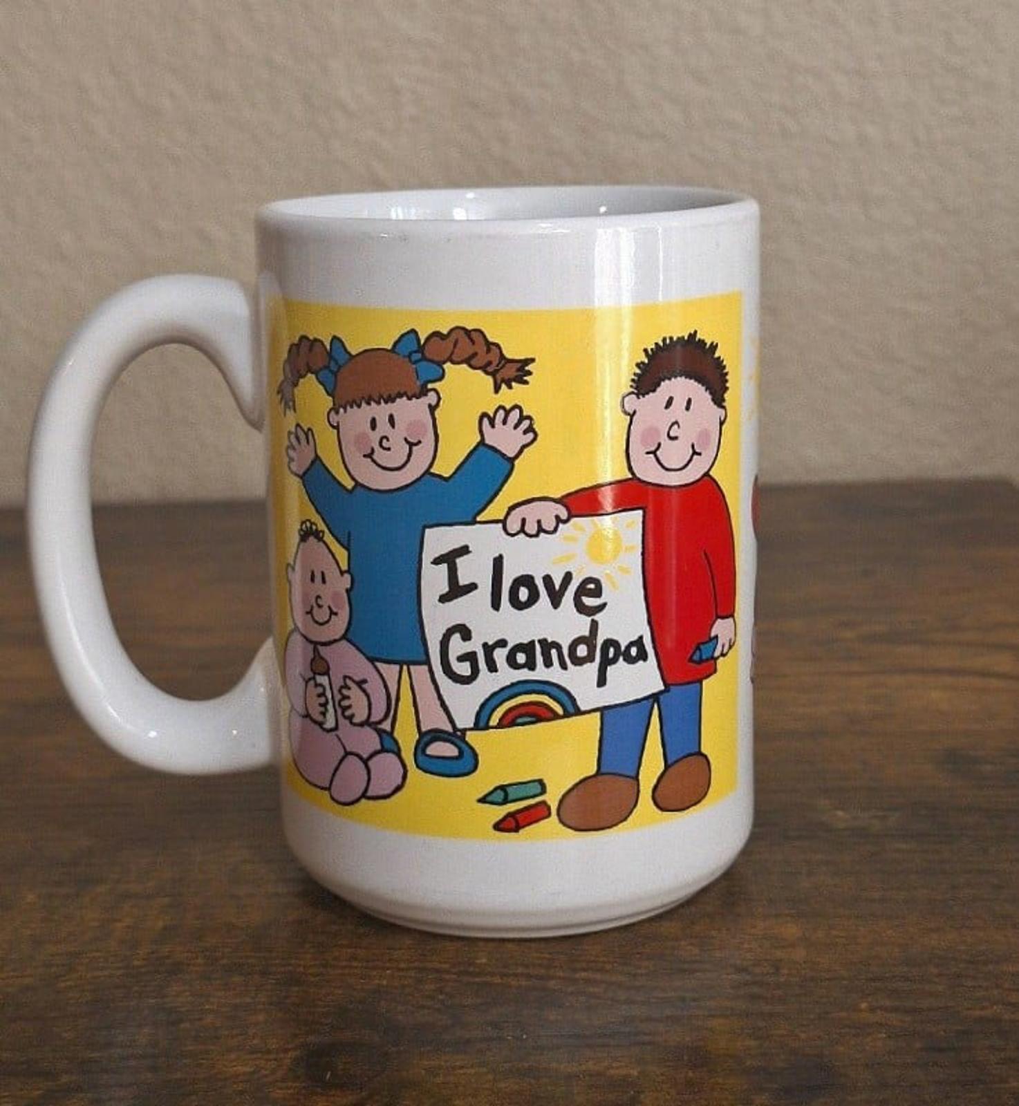 White ceramic mug with “I love Grandpa” sign and cartoon people, yellow-and-blue design