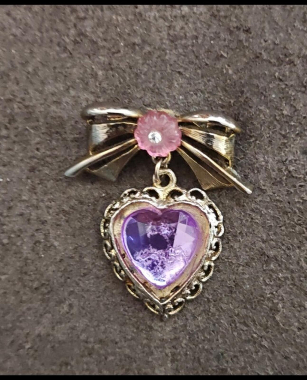 Purple heart-shaped gemstone brooch with ornate gold filigree and pink flower topper