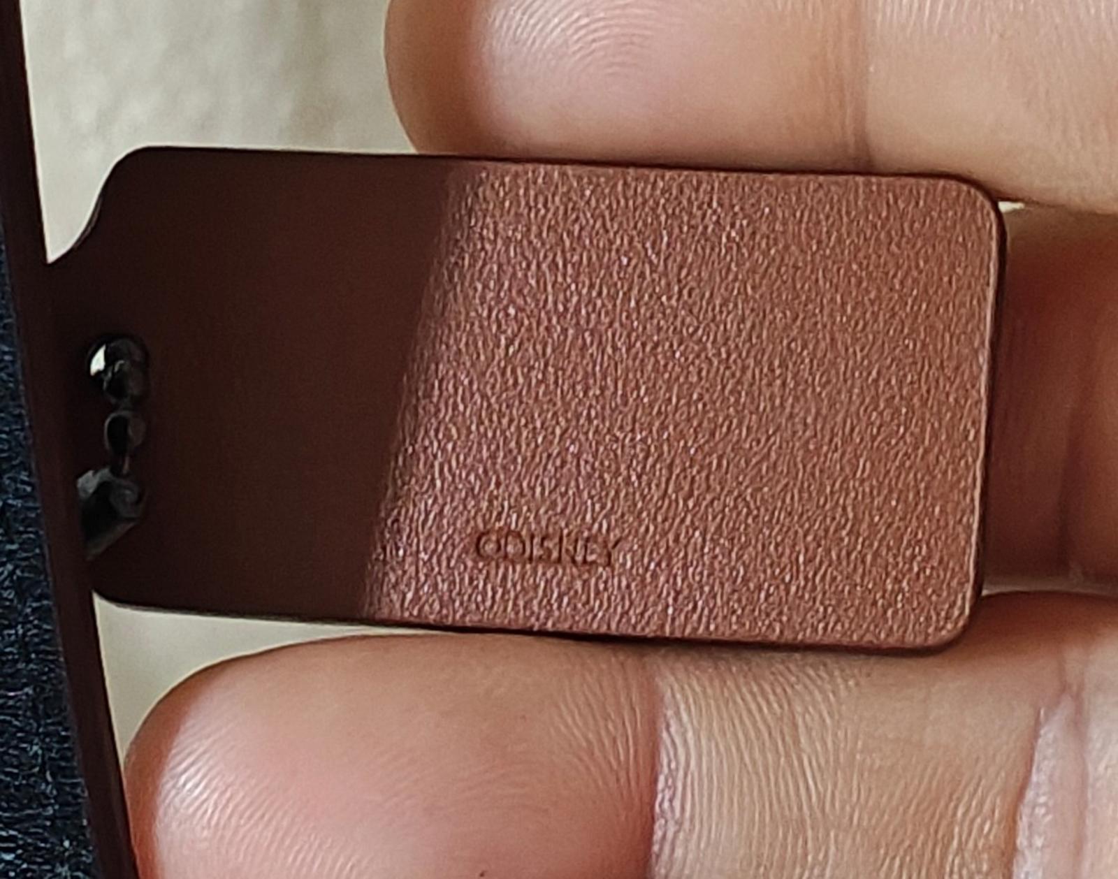 Brown leather Coach hang tag on strap with embossed logo, close-up