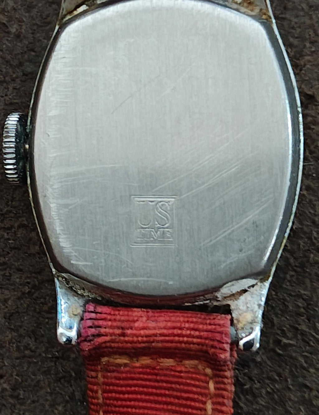 Vintage ladies wristwatch caseback on red strap, engraved logo on metal back.